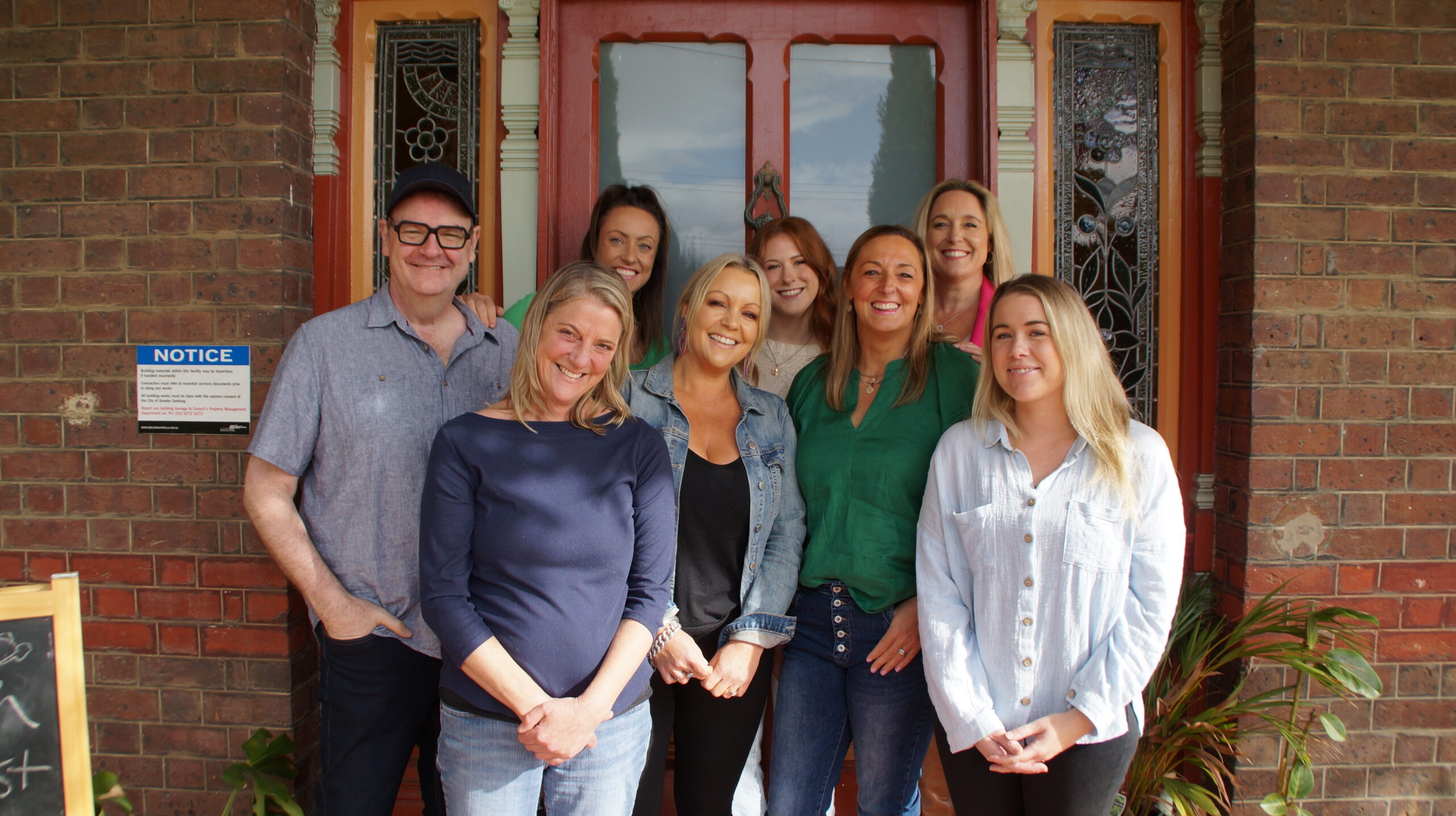 Spectrum Support Coordination Team standing together in front of a closed door of a brick house.