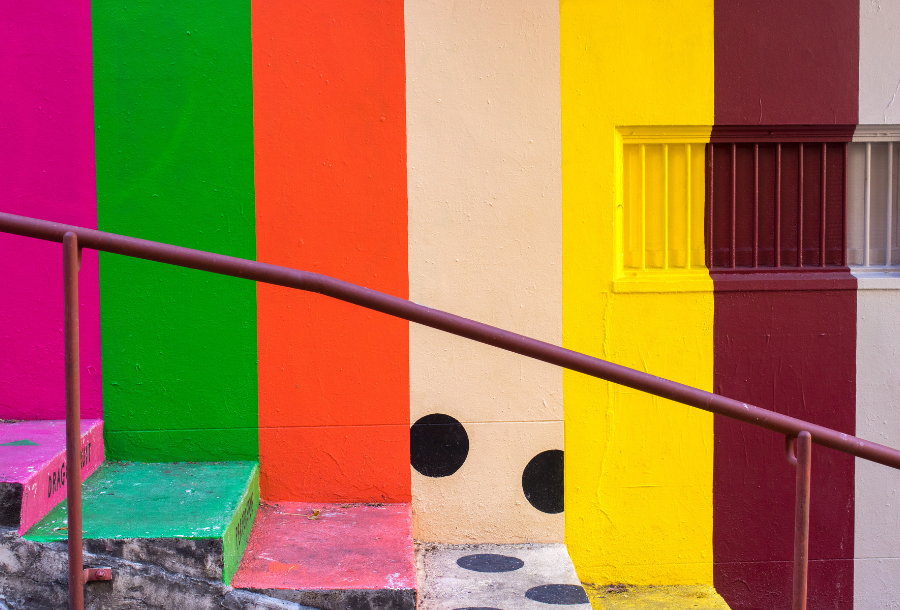 Concrete wall covered in beautiful rows of bright colours and the concrete steps, colours of bold pink, green, orange, tan with black polka dots, yellow and deep brown