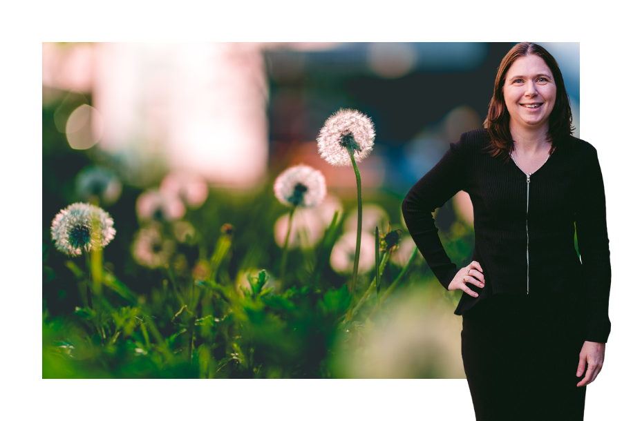 A close up picture of green grass with the sun peaking through and shining on a dandelion, standing next to the picture is Karlene Wightman.