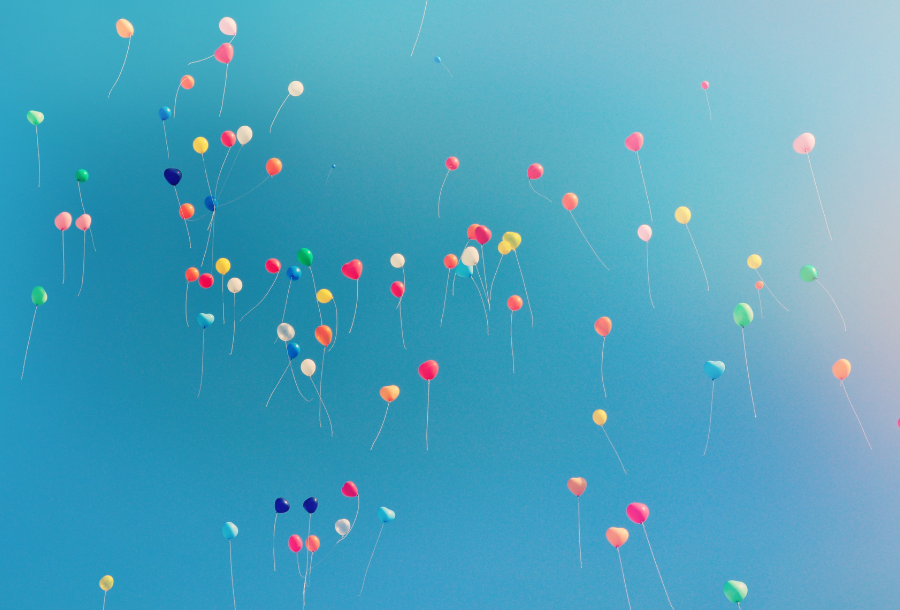 Pictured, a beautiful blue sky looking up where there is a sea of different coloured balloons floating up into the atmosphere