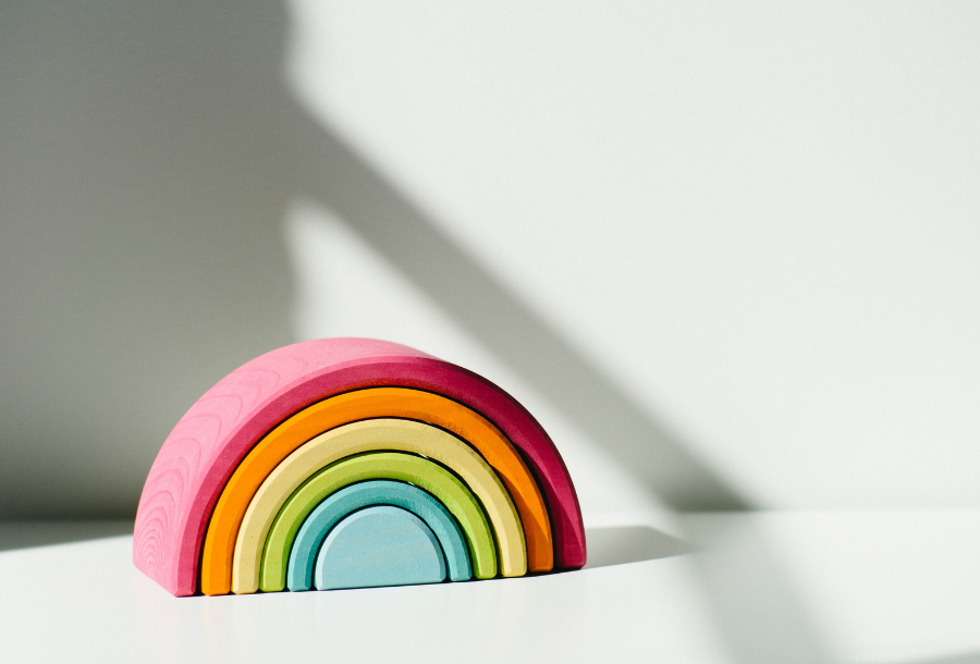 Pictured, a wooden rainbow in all the bright beautiful colours on a white bench